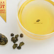 Load image into Gallery viewer, Hwa Gung Tea's award winning Eternity Series Reserved Snow Alpine Oolong Tea (1968) tea soup and ball shaped loose tea leaves